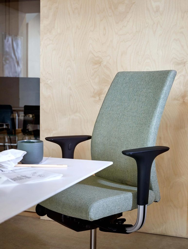 HÅG Creed 6006 green upholstered office chair with black armrests at a white desk in a modern office setting