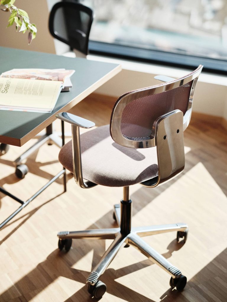 HÅG HÅG Tion mesh 2340 office chair with a mesh backrest and fabric seat at a desk with a laptop and magazines